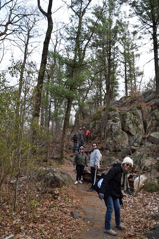 Walking along a path through a forest, with rock formations in the background