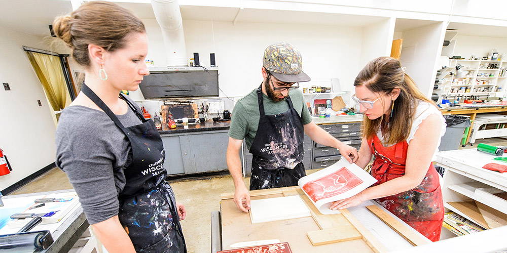 Students in a printmaking class look at a poster just off the press