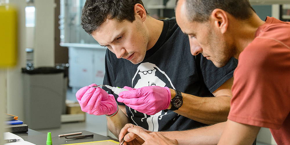 An entomology student and professor examine a specimen