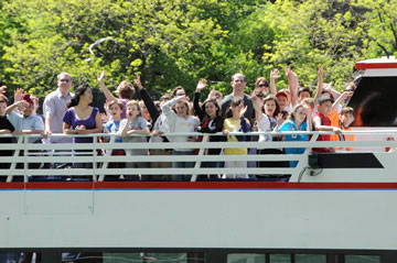 Group of people waving from the upper deck of a boat