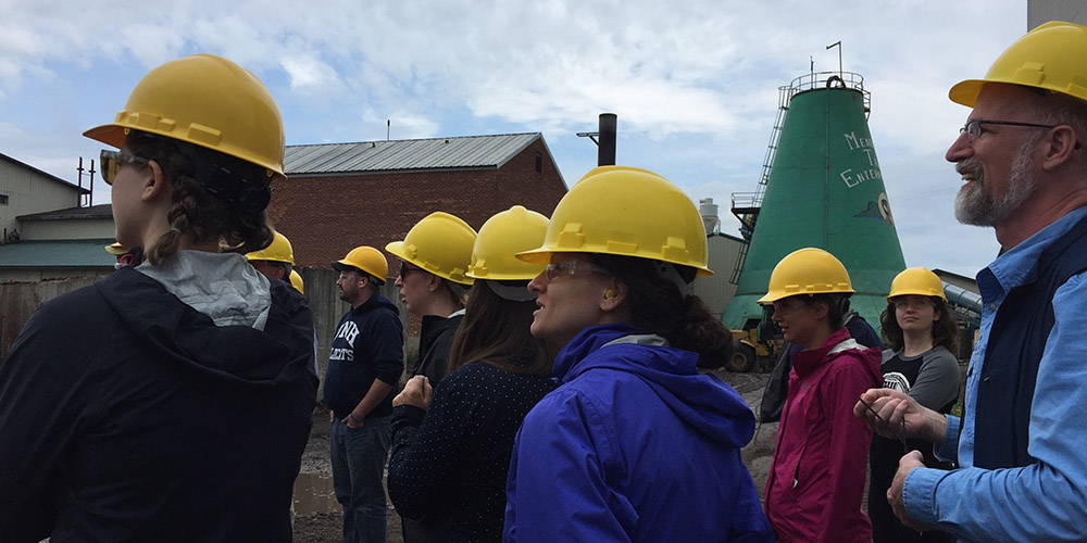 Workshop participants wear hard hats at a lumber mill