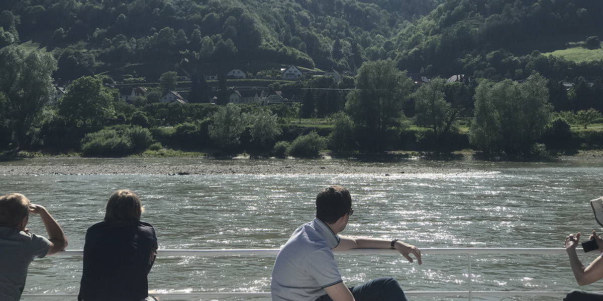 Students look out at a river with a hilly landscape on the opposite shore