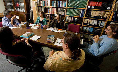 A small group of students sitting around a table discussing a book.