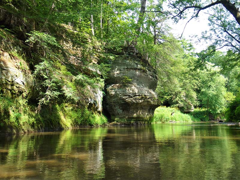 The Kickapoo River surrounded by rocky bluffs and lush tree cover.