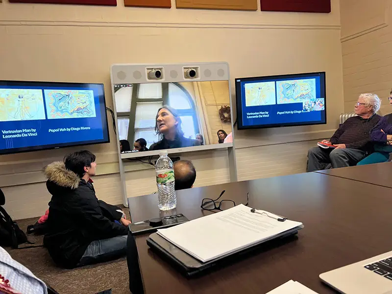 Audience members watch Kata Beilin speaking via teleconference