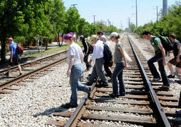 Group of people walking across two sets of railroad tracks