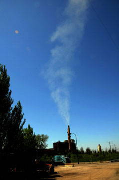 Distant photo of a smokestack emitting plumes of smoke